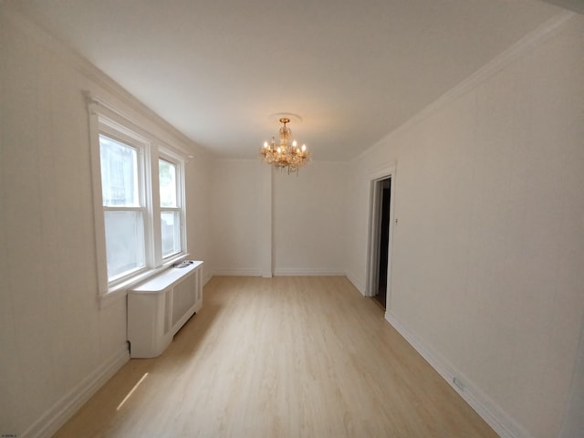 spare room featuring radiator, a notable chandelier, light hardwood / wood-style flooring, and ornamental molding