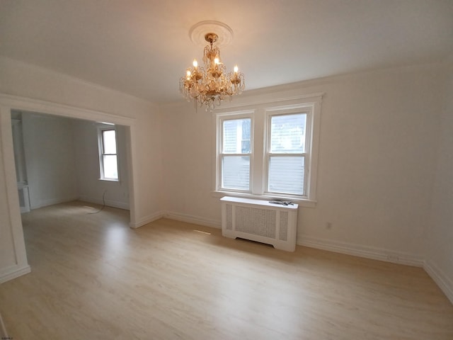 unfurnished room with radiator, light hardwood / wood-style floors, and a notable chandelier