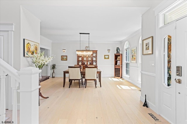 dining room featuring light hardwood / wood-style flooring, ornamental molding, decorative columns, and a wealth of natural light