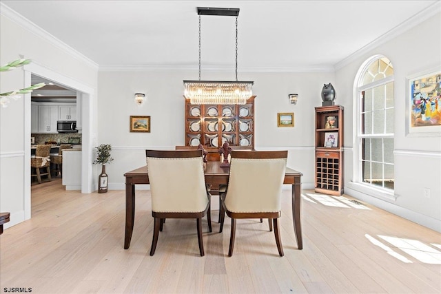 dining area featuring a notable chandelier, light wood-type flooring, ornamental molding, and a healthy amount of sunlight