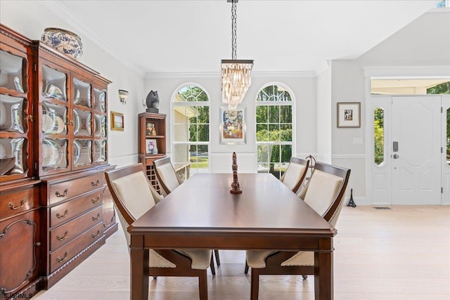 dining area featuring a notable chandelier, ornamental molding, and light hardwood / wood-style floors