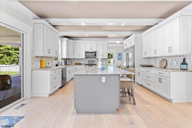 kitchen featuring a breakfast bar, appliances with stainless steel finishes, light hardwood / wood-style floors, and backsplash