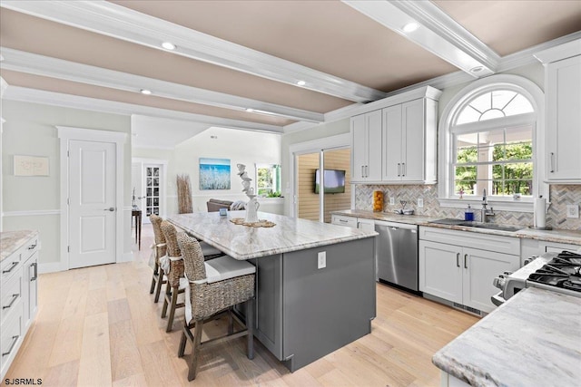 kitchen with beamed ceiling, a center island, dishwasher, and light hardwood / wood-style floors