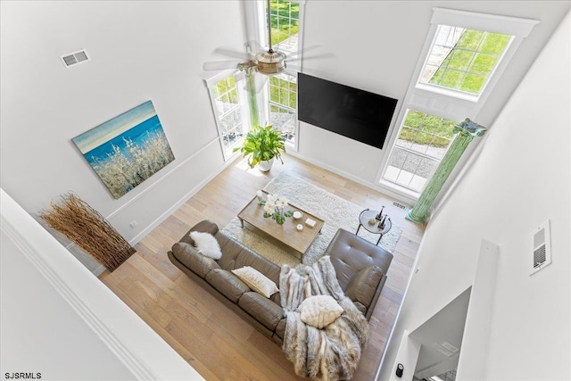 living room with ceiling fan, hardwood / wood-style floors, and a towering ceiling