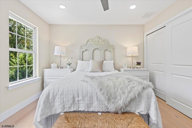 bedroom with light hardwood / wood-style flooring, a closet, and multiple windows