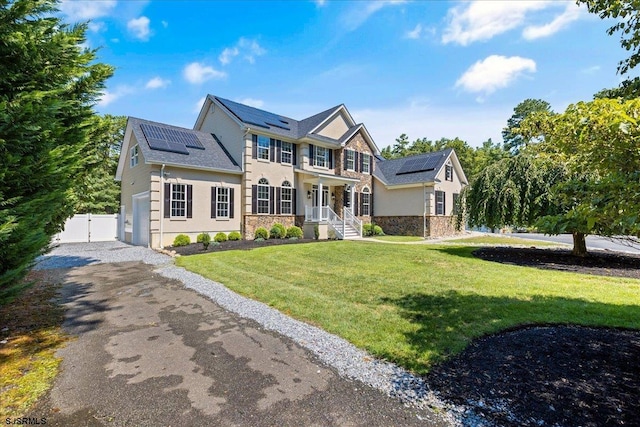 view of front of house with a front lawn and solar panels