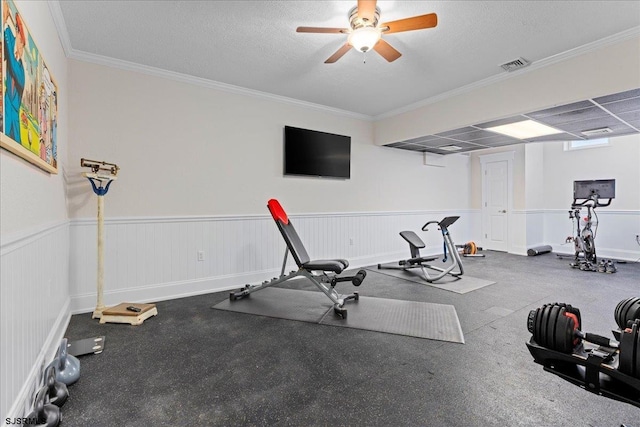 exercise area featuring ceiling fan, ornamental molding, and a textured ceiling