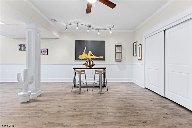 dining area featuring ceiling fan, crown molding, rail lighting, light wood-type flooring, and decorative columns