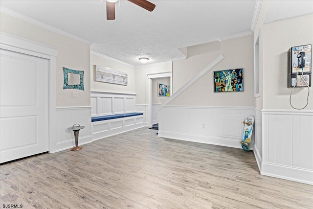 unfurnished living room with light hardwood / wood-style flooring, a textured ceiling, crown molding, and ceiling fan