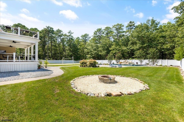 view of yard featuring a swimming pool, ceiling fan, and a fire pit