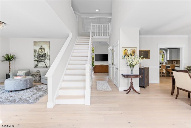 entrance foyer featuring light wood-type flooring and a towering ceiling