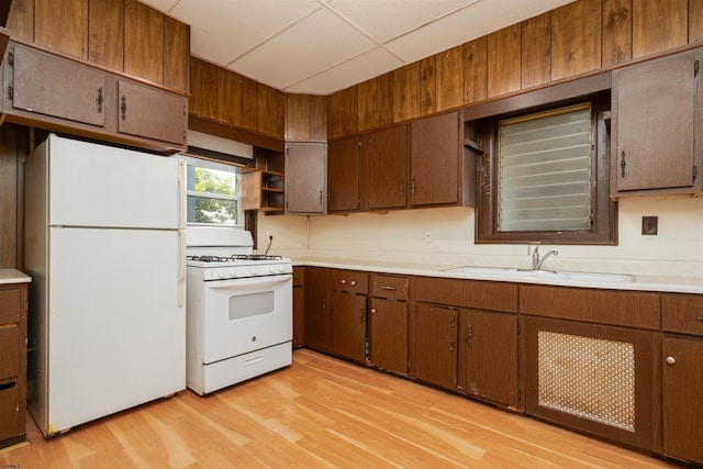 kitchen with sink, a paneled ceiling, white appliances, and light hardwood / wood-style floors