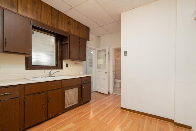 kitchen featuring dark brown cabinets, sink, a paneled ceiling, and light hardwood / wood-style floors