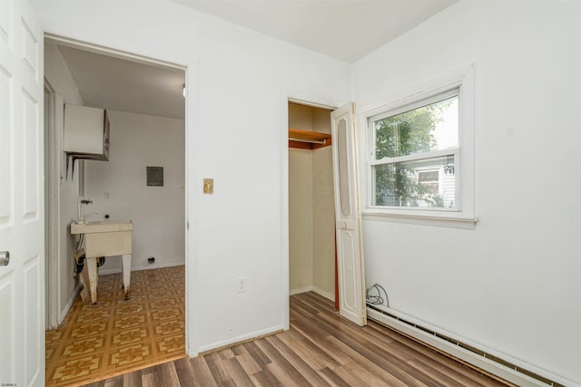 unfurnished bedroom featuring hardwood / wood-style flooring, a baseboard heating unit, and a closet