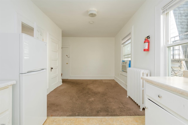 hallway with cooling unit, radiator, and light carpet