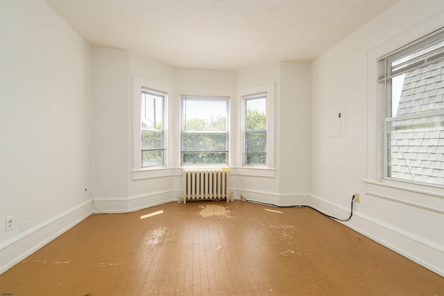 unfurnished room with hardwood / wood-style flooring and radiator heating unit