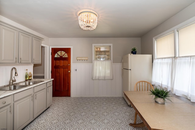 kitchen with gray cabinetry, sink, an inviting chandelier, and white refrigerator