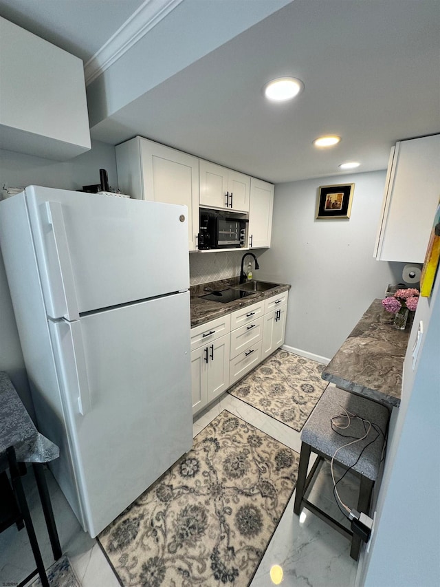 kitchen featuring a breakfast bar, white refrigerator, white cabinetry, ornamental molding, and light tile patterned floors