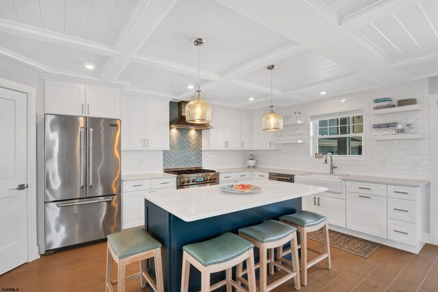 kitchen featuring stainless steel appliances, backsplash, a center island, coffered ceiling, and wall chimney exhaust hood