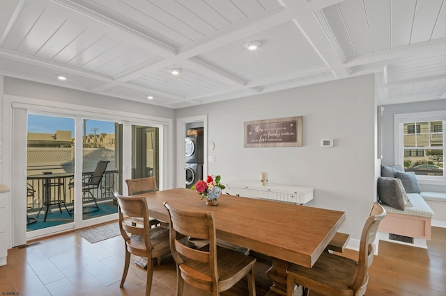 dining space with beam ceiling, stacked washing maching and dryer, and coffered ceiling