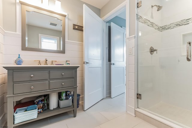 bathroom featuring a shower with shower door, vanity, and tile patterned floors