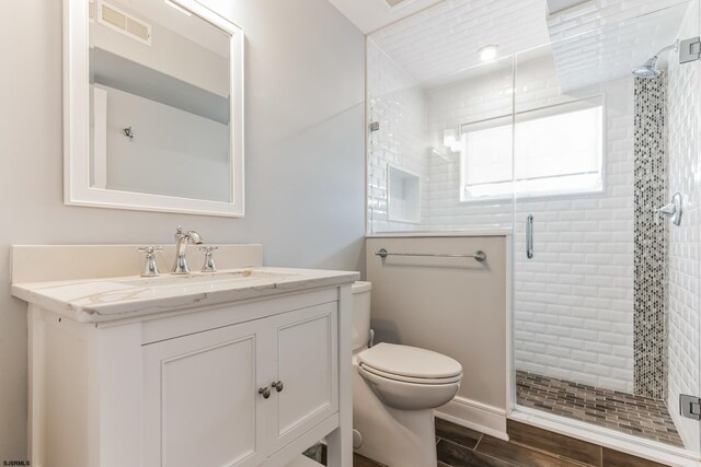 bathroom with toilet, hardwood / wood-style floors, vanity, and an enclosed shower