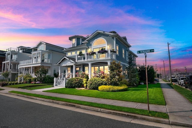 view of front facade featuring a balcony and a lawn