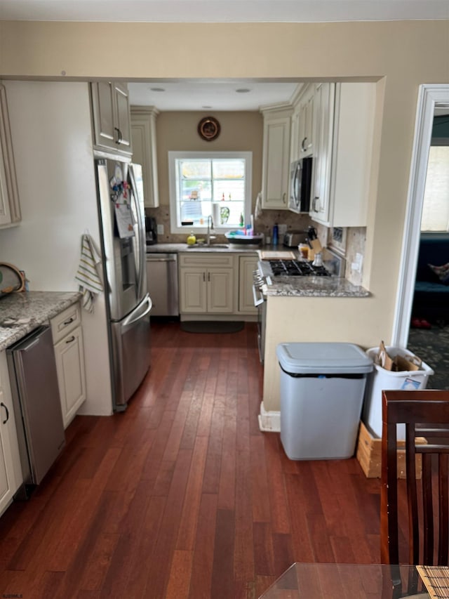 kitchen featuring dark wood-type flooring, stainless steel appliances, sink, and light stone counters