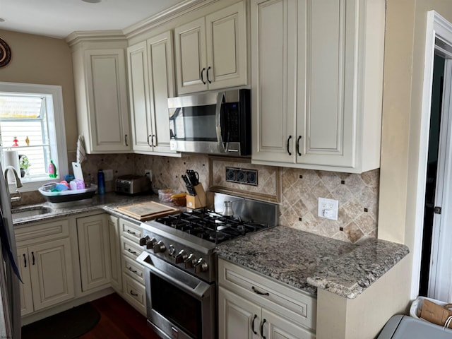 kitchen featuring light stone counters, stainless steel appliances, sink, and decorative backsplash