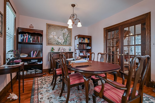 dining area with a notable chandelier, french doors, and hardwood / wood-style flooring