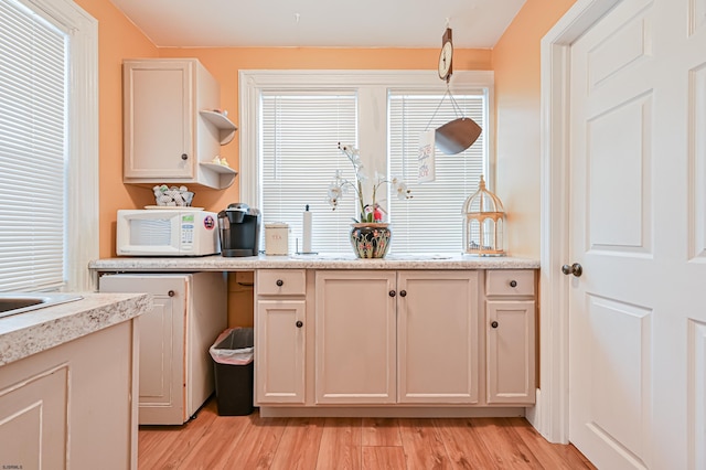 kitchen with light hardwood / wood-style flooring, cream cabinetry, and decorative light fixtures