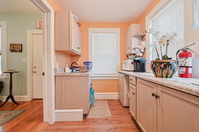 kitchen with light hardwood / wood-style flooring, sink, and light stone countertops