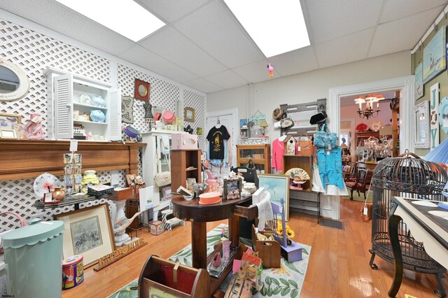 misc room featuring a drop ceiling, an inviting chandelier, and light hardwood / wood-style floors