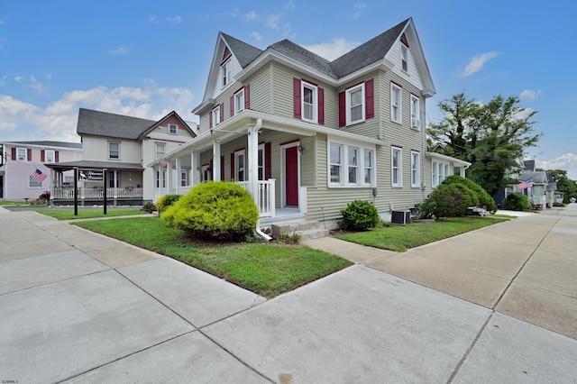 view of front of property with a front lawn, cooling unit, and a porch