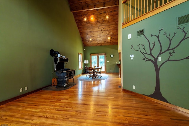 living area featuring visible vents, baseboards, wood finished floors, and a towering ceiling