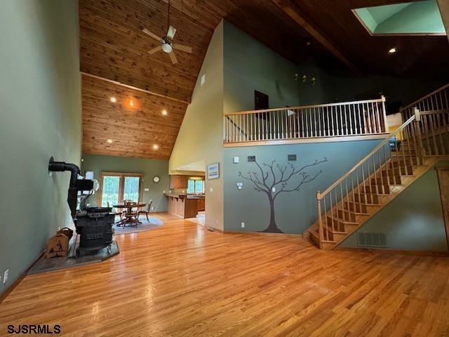 living room featuring stairway, high vaulted ceiling, ceiling fan, and wood finished floors