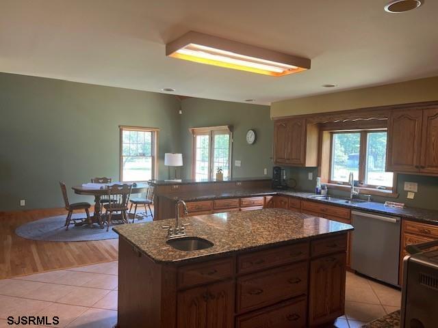 kitchen with light tile patterned flooring, plenty of natural light, dishwasher, and a sink