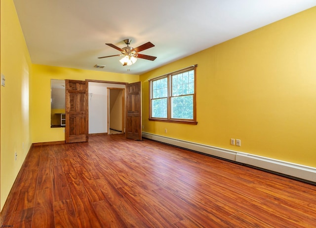 unfurnished bedroom featuring a baseboard heating unit, wood finished floors, baseboards, and ceiling fan