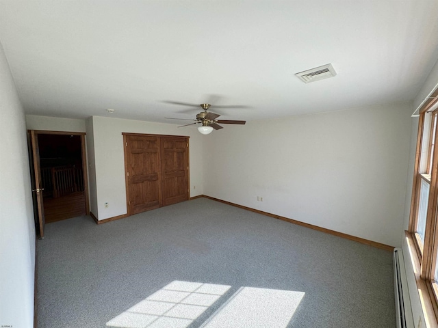 unfurnished bedroom featuring visible vents, light carpet, a closet, a baseboard radiator, and baseboards