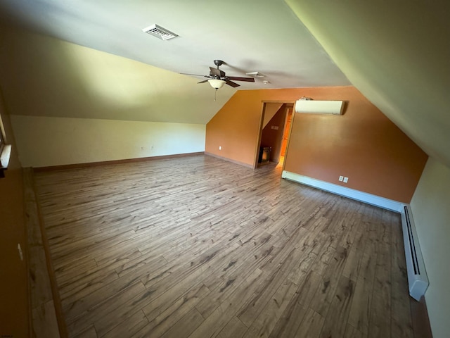 bonus room featuring a ceiling fan, wood finished floors, visible vents, vaulted ceiling, and baseboard heating