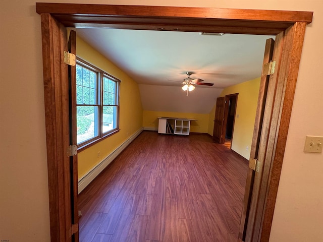 unfurnished living room with a baseboard heating unit, dark wood finished floors, baseboards, ceiling fan, and vaulted ceiling