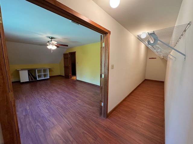 hall with baseboards, wood finished floors, and vaulted ceiling