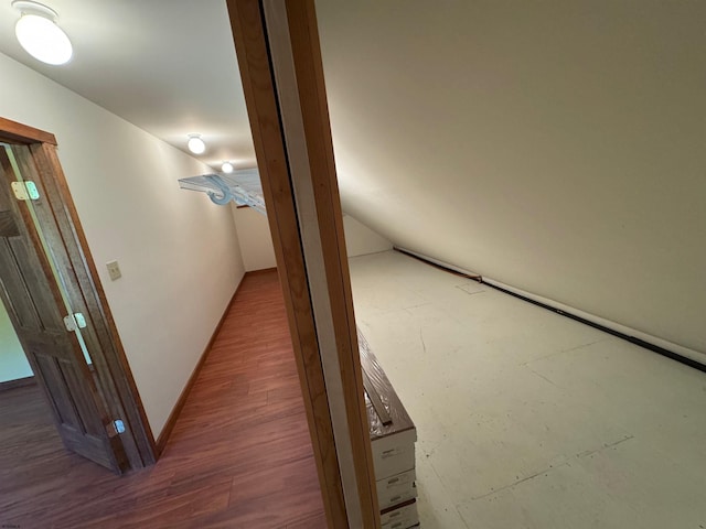 hall featuring lofted ceiling, wood finished floors, and baseboards