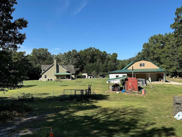 view of yard with a garage, fence, an outdoor structure, and a pole building