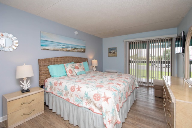 bedroom with a textured ceiling, access to outside, and light hardwood / wood-style flooring