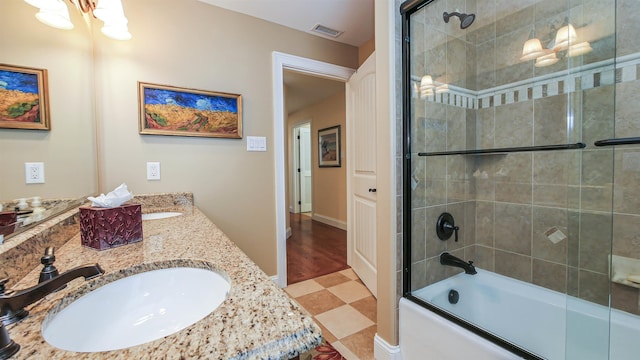 bathroom with tile patterned floors, dual vanity, and bath / shower combo with glass door