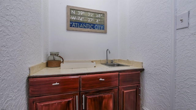 bar featuring a textured wall and a sink