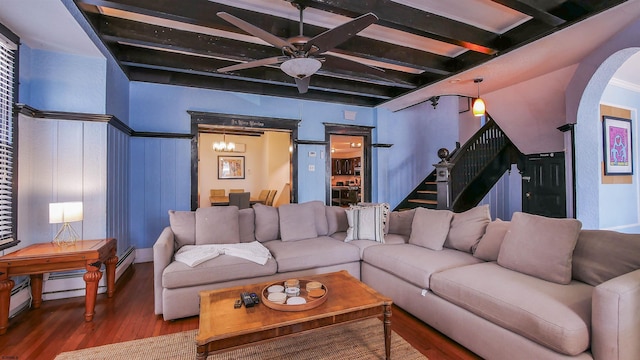 living room featuring beamed ceiling, ceiling fan with notable chandelier, wood finished floors, stairway, and arched walkways