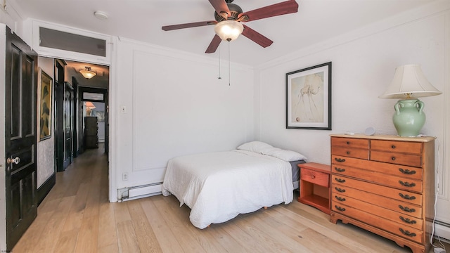 bedroom with baseboard heating, light wood-style flooring, crown molding, and a ceiling fan