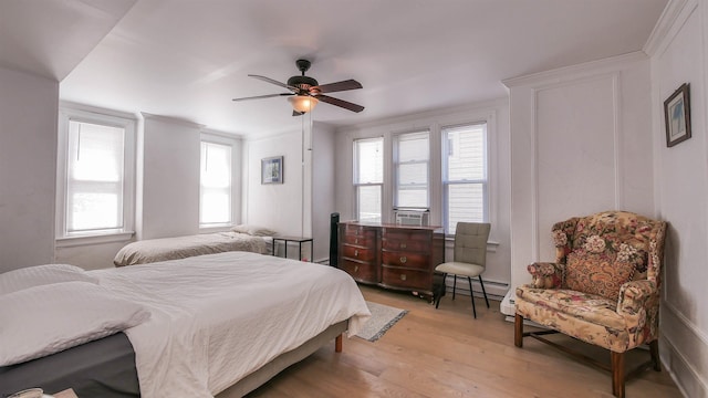 bedroom featuring multiple windows, light wood-type flooring, baseboard heating, and ornamental molding